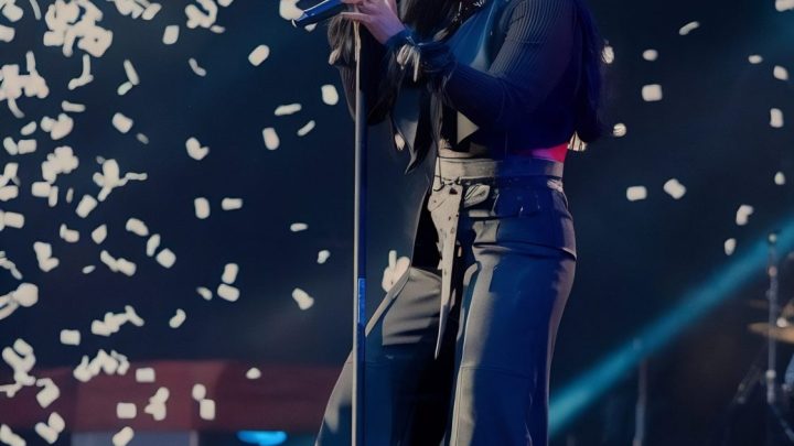 JoeyStarr chante sur scène, un microphone à la main, devant le public.